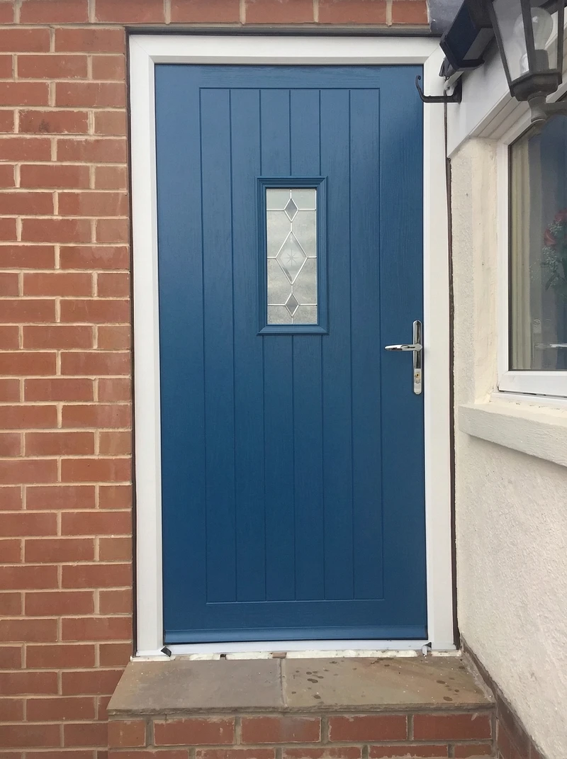Blue composite front door with diamond glass on red brick property